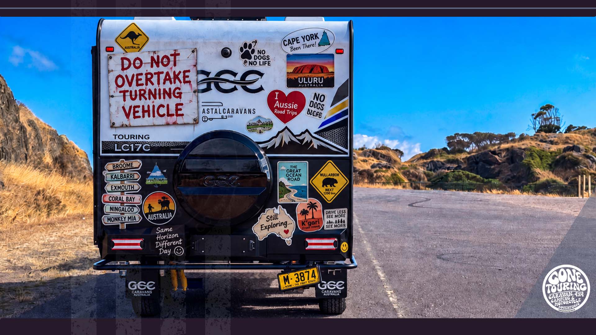 Caravan rear with hand-painted Do Not Overtake Turning Vehicle sign and travel stickers